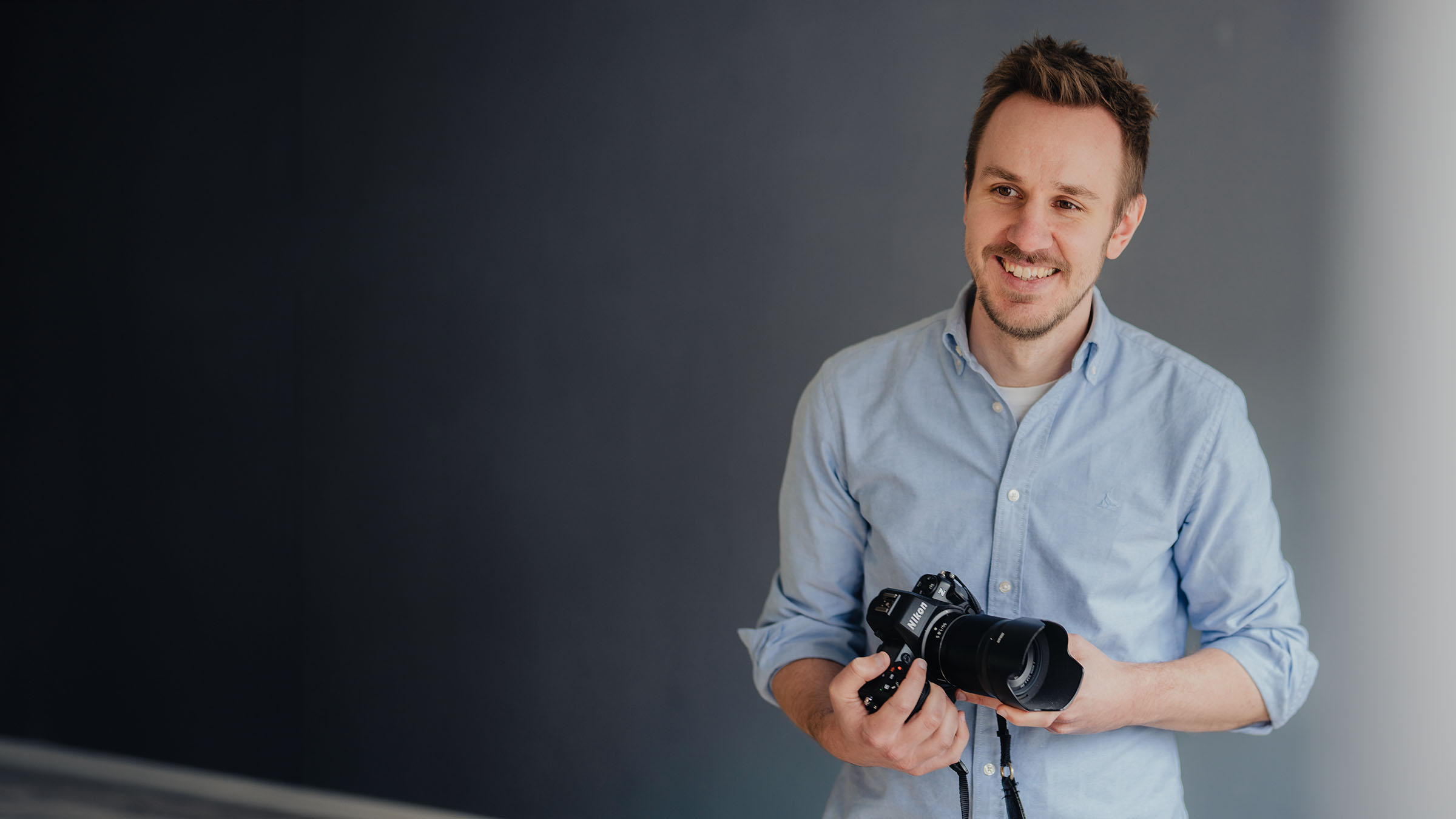 Home 7 Fotograf Marius Becker, lachend mit Kamera in der Hand