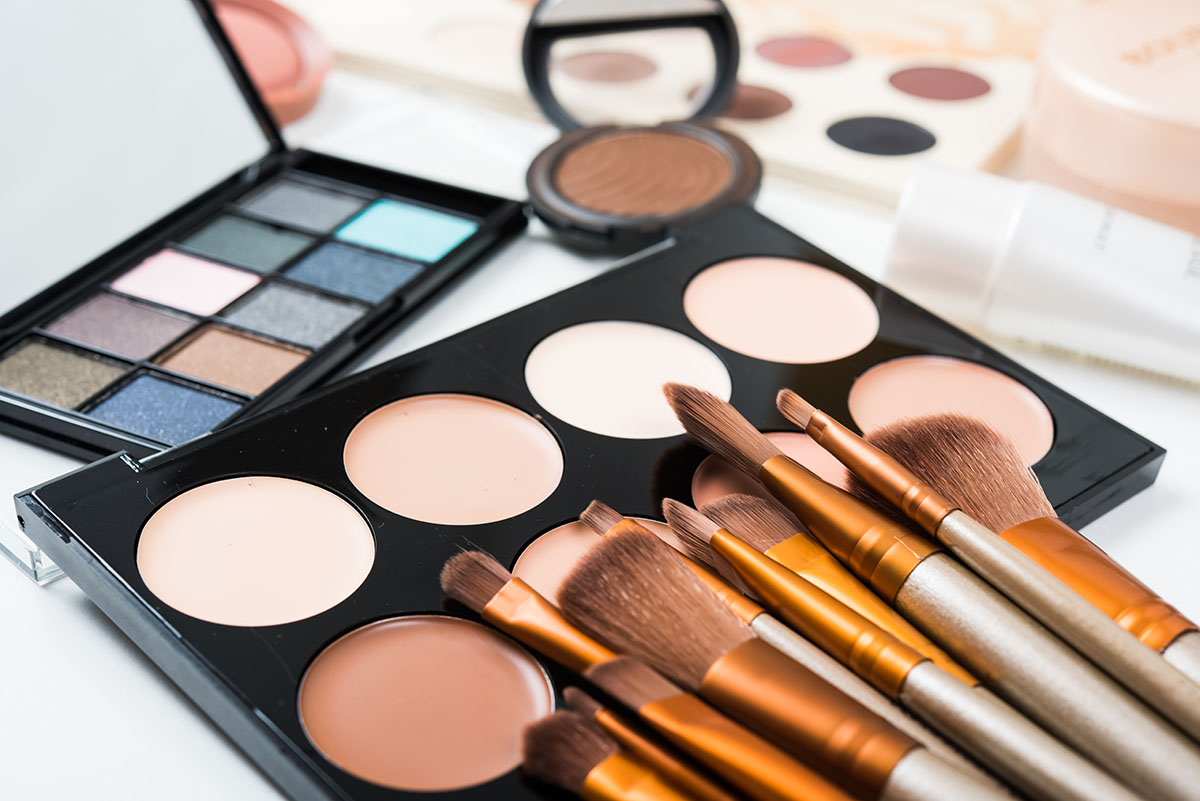 Professionelle Make-Up-Pinsel und Puder liegen auf einem weißen Tisch