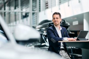 Businessfotos Düsseldorf 12 Geschäftsmann mit Tablet und Kaffee in einem modernen Autohaus, Businessfotos Köln