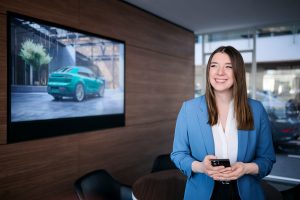 Businessfotos Düsseldorf 9 Mitarbeiterin im modernen Porsche Showroom mit Smartphone