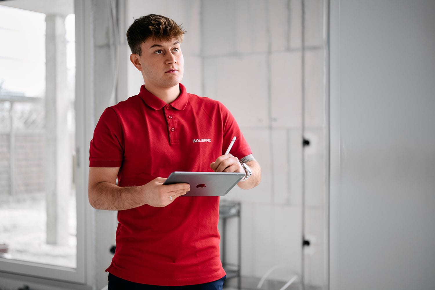 Handwerksfotografie - Authentische Bilder für ISOLIERFIX 2 Ein Handwerker steht mit einem ipad im Rohbau und begutachtet eine Wand
