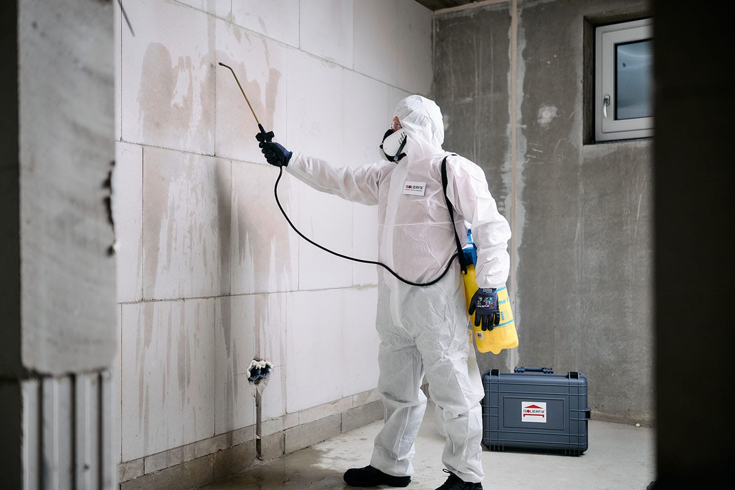 Handwerksfotografie - Authentische Bilder für ISOLIERFIX 3 Ein Handwerker in einem Schutzanzug sprüht eine Wand ein