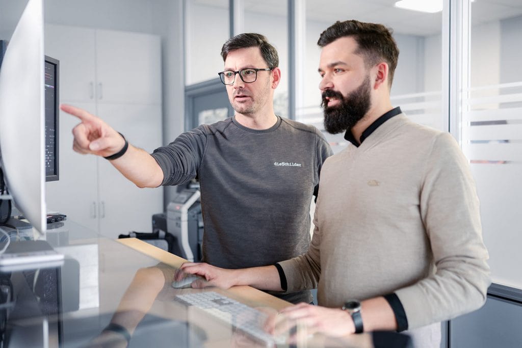 Unternehmensfotos für "die Schilder" 4 Zwei Männer stehen in einem Büro vor einem Bildschirm
