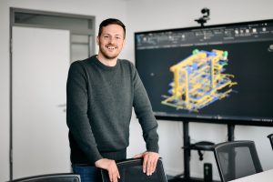 Mitarbeiterfoto eines Ingenieurs im Besprechungsraum mit technischer 3D-Planung auf dem Bildschirm