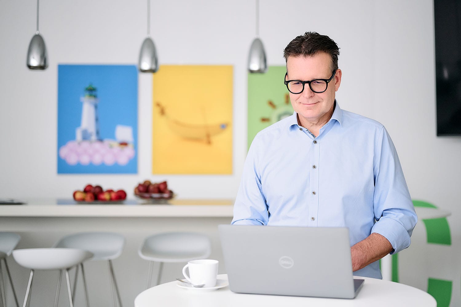 Ein Geschäftsmann steht mit seinem Laptop an einem Stehtisch