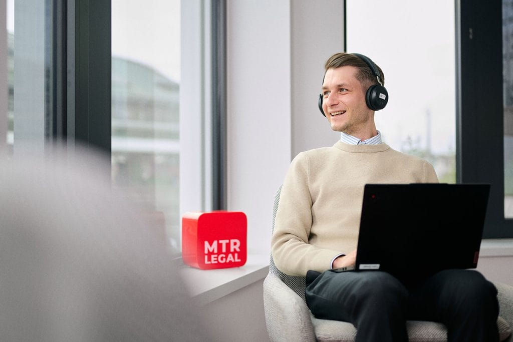Businessfotos für Rechtsanwälte, Kanzleien und Steuerberater 5 Ein Anwalt sitzt mit Headset und Laptop auf dem Schoß im Büro und blickt aus dem Fenster